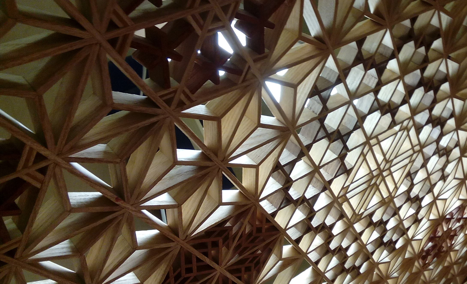 Several kumiko lattice patterns assembled in wood, photographed as a panel of geometric fillings